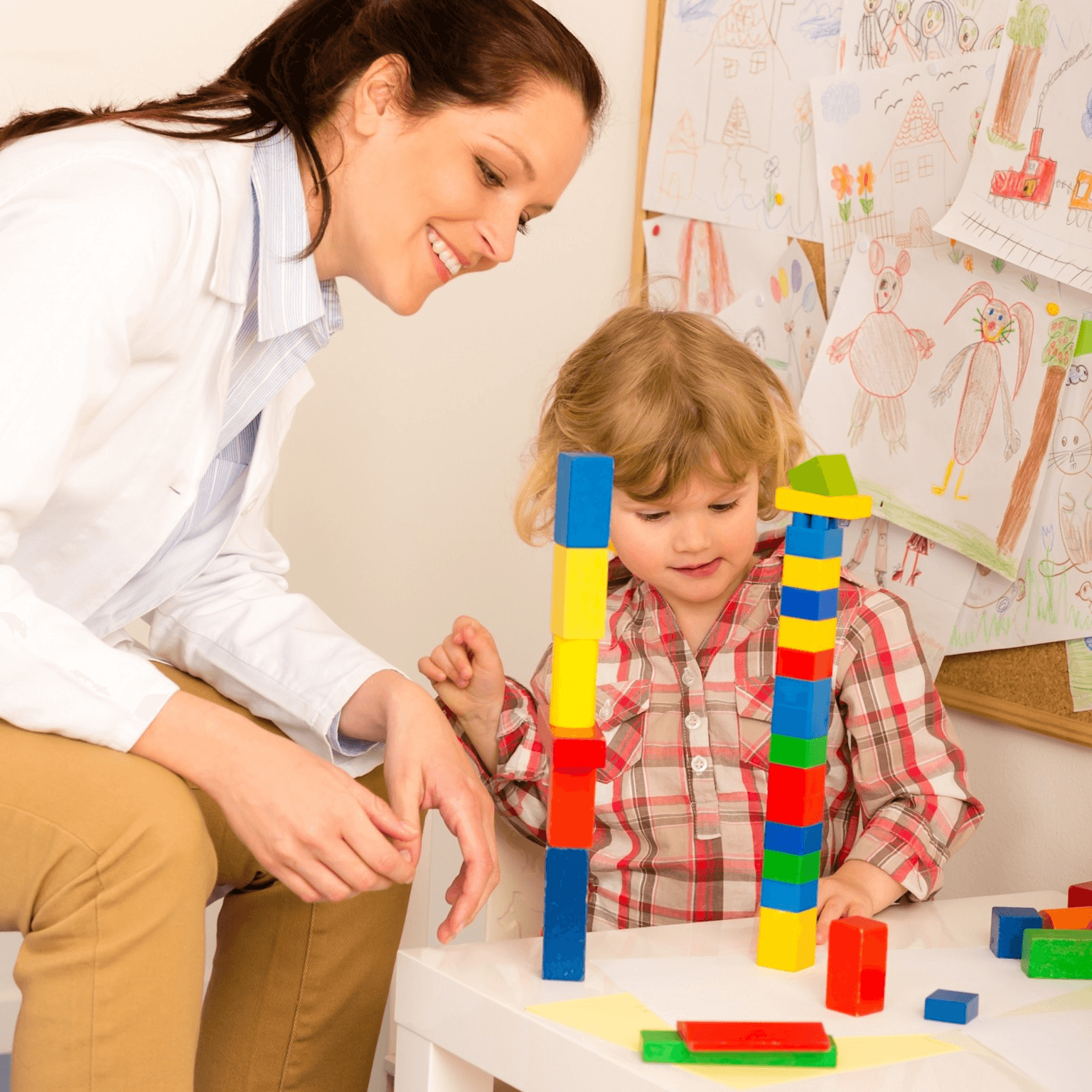Child engaged in an ABA therapy session with a therapist using colorful blocks to support learning and development.